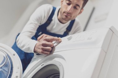 Çamaşır makinesini tamir eden tamirci, profesyonel servis konseptini ayarlıyor.