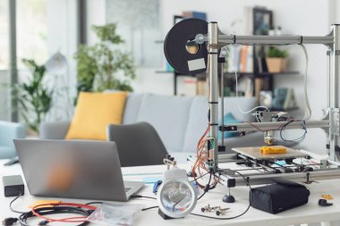 Evdeki bir masaüstünde 3D yazıcı dizüstü ve araçlar