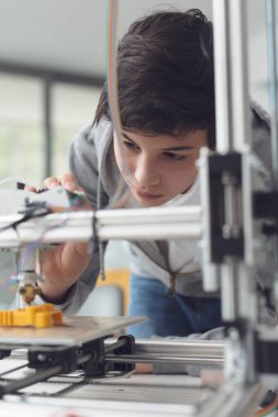 Akıllı genç öğrenci 3D baskı öğreniyor, yazıcıyı kontrol ediyor.