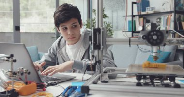 Akıllı öğrenci evde 3D yazıcı kullanıyor. Bilgisayarda bir prototip yaratıyor.