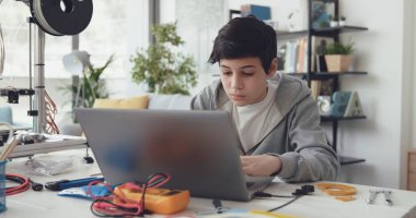 Evde fen ve teknoloji öğrenen yaratıcı çocuk, bir dizüstü bilgisayara bağlanıyor.