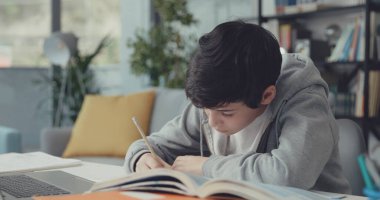 Akıllı odaklı öğrenci masada oturuyor ve çalışıyor, o ödevini yapıyor.