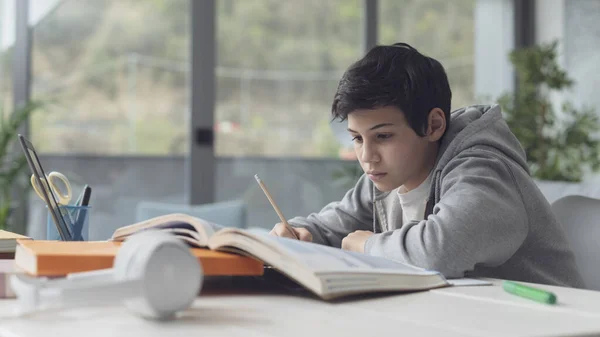 Χαριτωμένο Αγόρι Που Σπουδάζει Στο Σπίτι Διαβάζει Βιβλία Και Γράφει — Φωτογραφία Αρχείου