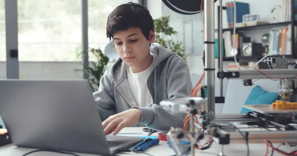 Intelligent student using a 3D printer at home, he is designing a prototype on the laptop