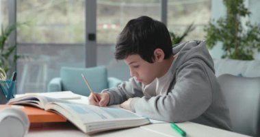 Öğrenci masada oturuyor ve ödev yapıyor.