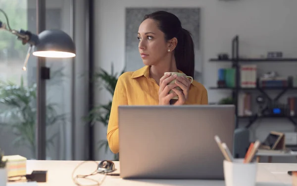 Mujer Joven Sentada Escritorio Oficina Tomando Café Ella Está Mirando —  Fotos de Stock