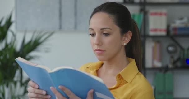 Jovem mulher lendo um livro e sorrindo — Vídeo de Stock