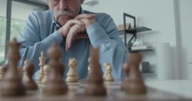 Son sınıf öğrencisi evde satranç oynuyor.