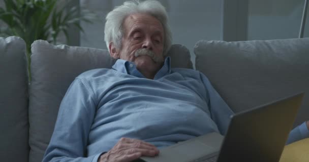 Luie senior man wakker worden en met behulp van een laptop — Stockvideo