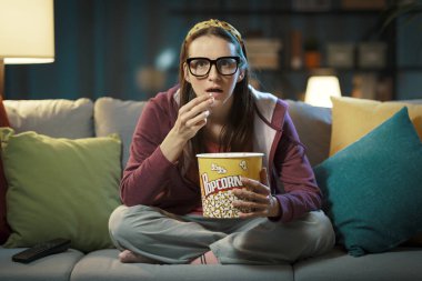 Woman watching a suspense movie and eating popcorn clipart