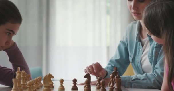 Young mother teaching chess to her daughters – stockvideo