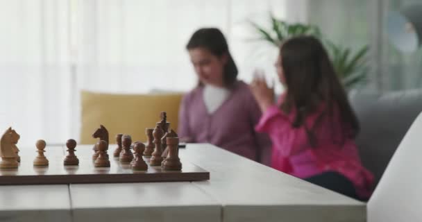 Girls sitting together and chessboard in the foreground — Vídeo de stock