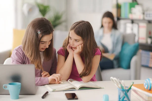 Girl Helping Her Younger Sister Her Homework Sitting Desk Reading — Stockfoto