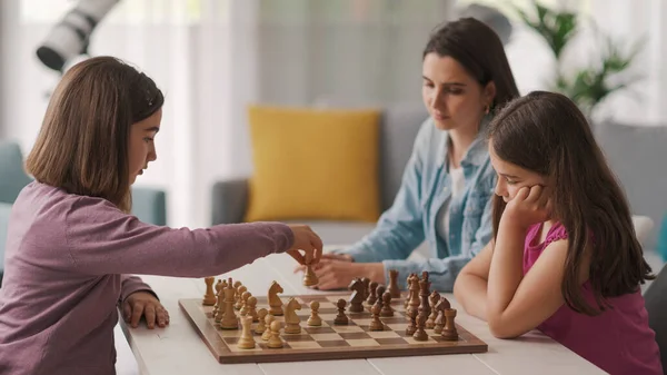 Girls Playing Chess Together Home Mother Sitting Next Them Watching — Φωτογραφία Αρχείου