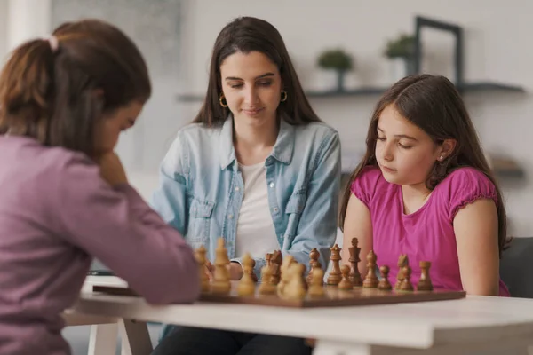 Girls Playing Chess Together Home Mother Sitting Next Them Watching — Φωτογραφία Αρχείου