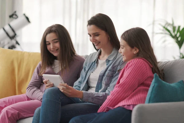 Happy Girls Sitting Sofa Connecting Digital Tablet Watching Movies Online — Zdjęcie stockowe