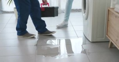 Tesisatçı sızdıran bir çamaşır makinesini kontrol ediyor.