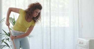 Çamaşır makinesi sızdırıyor ve kadın temizliği yapıyor.