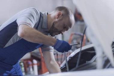 Tamircide tamirci araba motoru tamir ediyor.