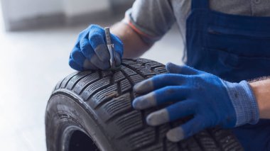 Tamirci lastik izi derinliğini kontrol ediyor ve lastik göstergesi, araba bakım konsepti kullanıyor.