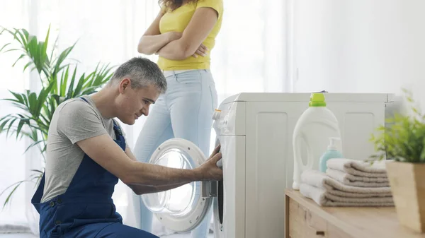 壊れた洗濯機をチェック修理工 顧客は彼の隣に立っている 修理サービスの概念 — ストック写真
