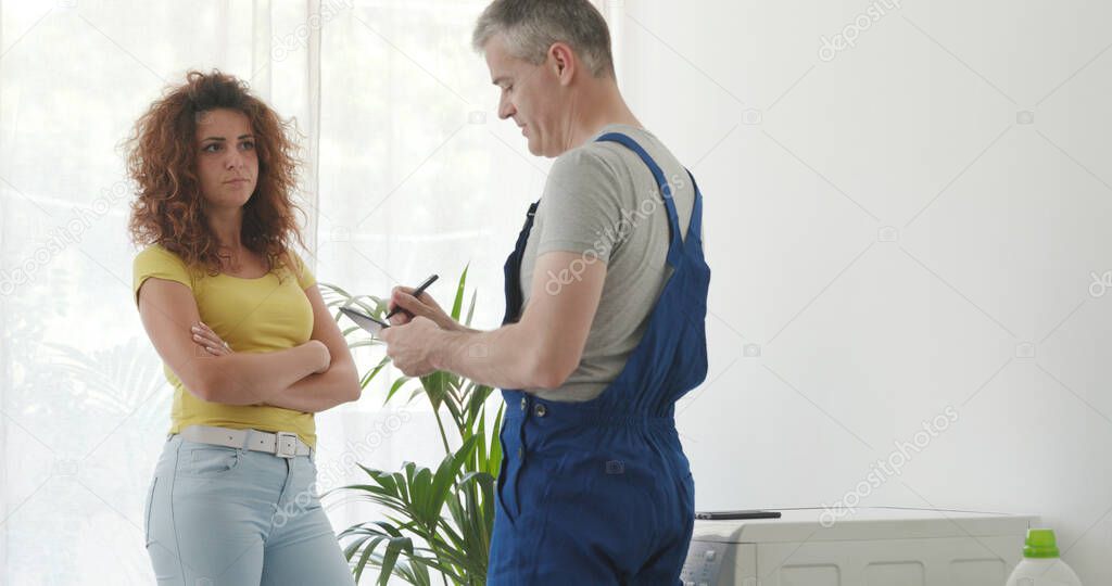 Woman talking with a professional repairman, he is writing on a clipboard