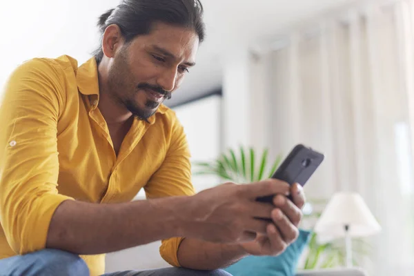 Giovane Seduto Sul Divano Casa Chattare Con Suo Smartphone Comunicazione — Foto Stock