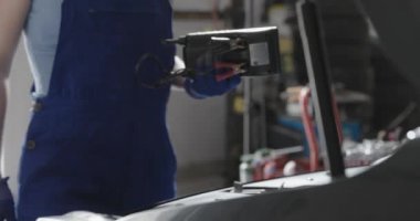 Kadın tamirci araba aküsünü test ediyor.