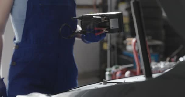 Feminino mecânico testando uma bateria de carro — Vídeo de Stock