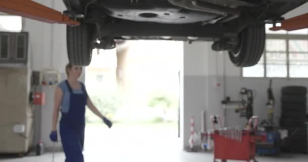 Mecánica femenina trabajando bajo un coche — Vídeo de stock