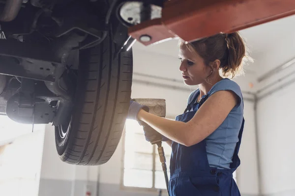 汽车修理厂的专业女机械师进行轮式更换 — 图库照片