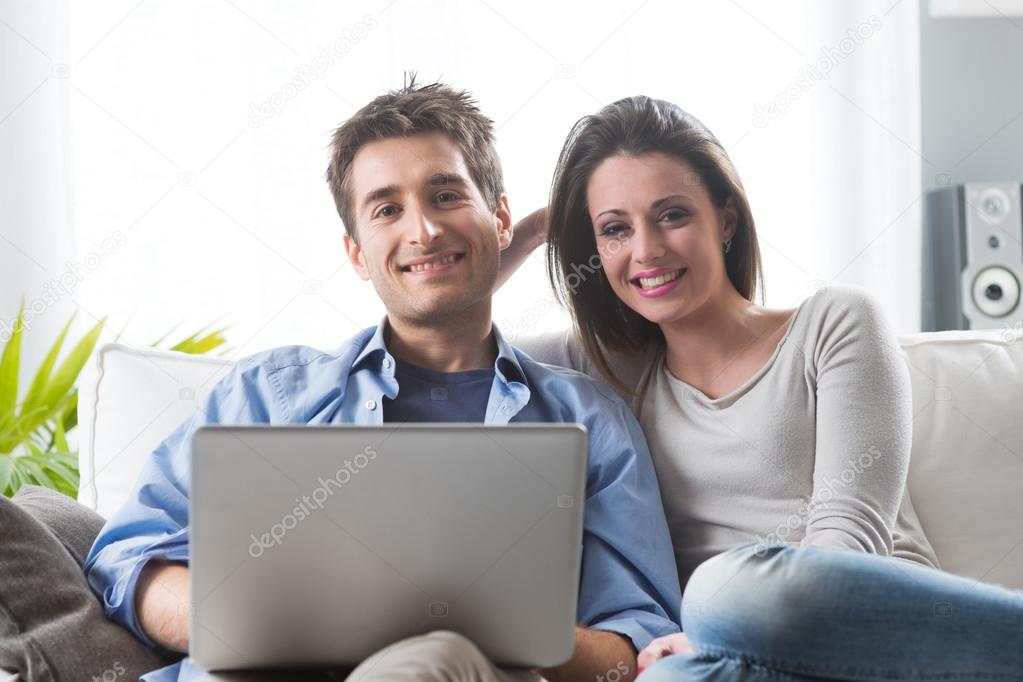 Couple relaxing on sofa with laptop