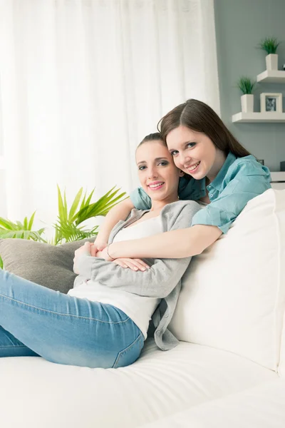 Freundinnen umarmen sich auf dem Sofa — Stockfoto