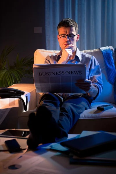 Businessman reading newspaper late at night — Stock Photo, Image