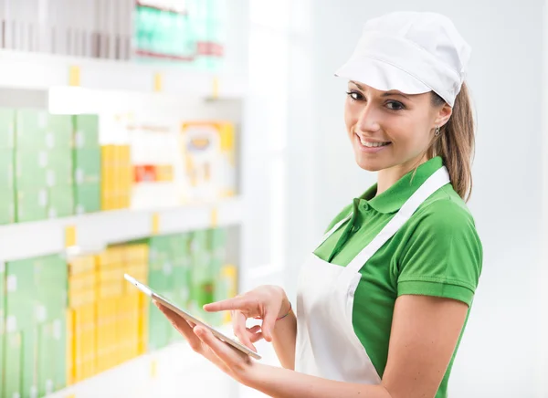 Vrouwelijke verkoopbediende met tablet in supermarkt — Stockfoto