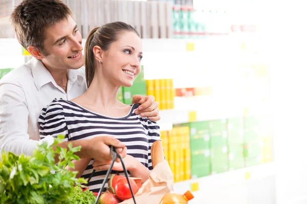 Happy young couple at supermarket — Stock Photo, Image
