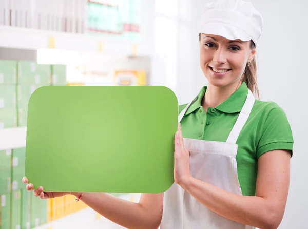 Female sales clerk with green sign — Stock Photo, Image