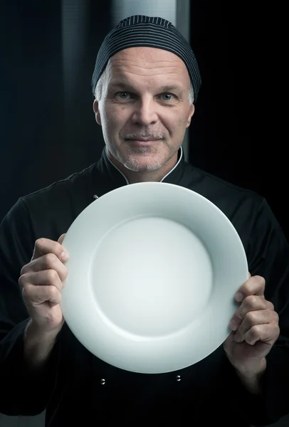 Chef en uniforme negro mostrando un plato — Foto de Stock