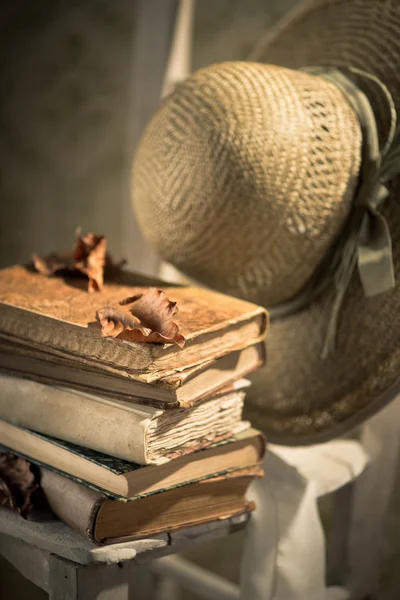 Straw hat and old books on chair — Stock Photo, Image