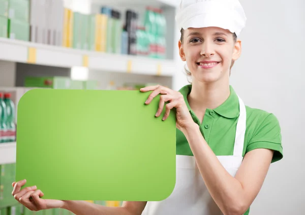 Female sales clerk with green sign — Stock Photo, Image