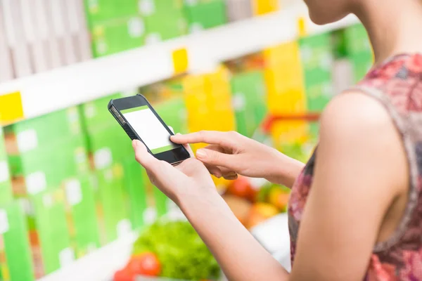 Vrouw met mobiele telefoon op supermarkt — Stockfoto