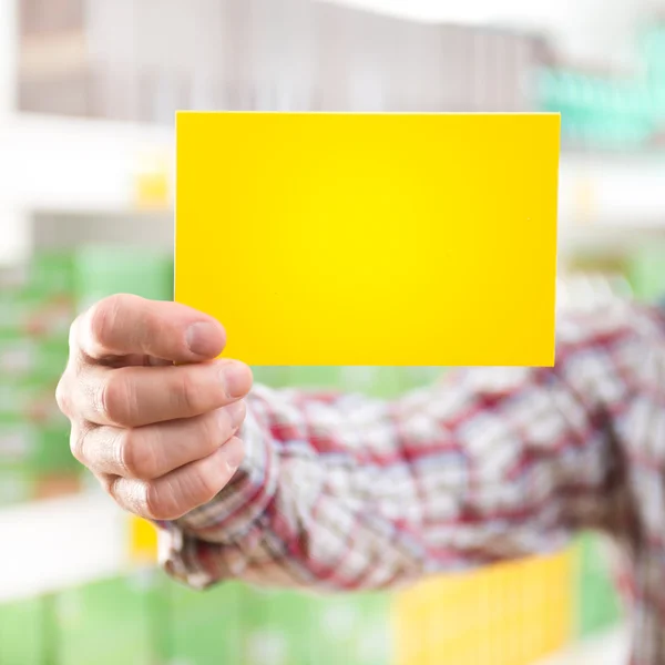 Hombre sosteniendo cartel amarillo en el supermercado — Foto de Stock