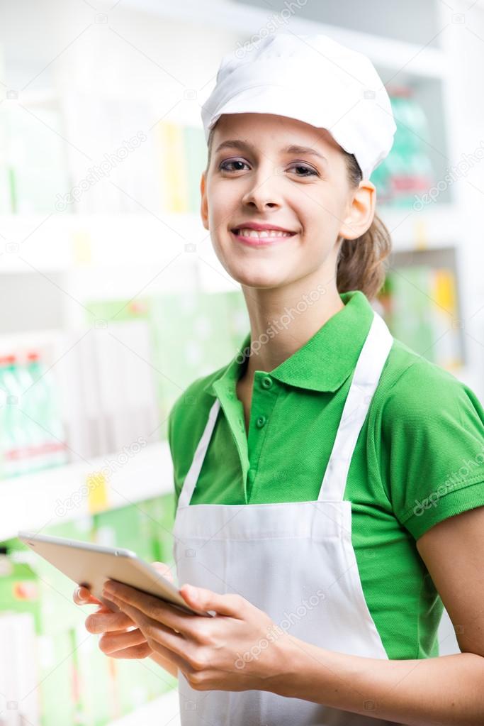 Female sales clerk with tablet at supermarket