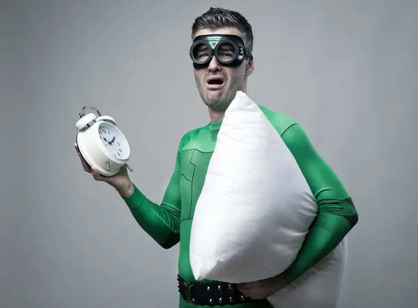 Sleepy superhero yawning with clock and pillow — Stock Photo, Image