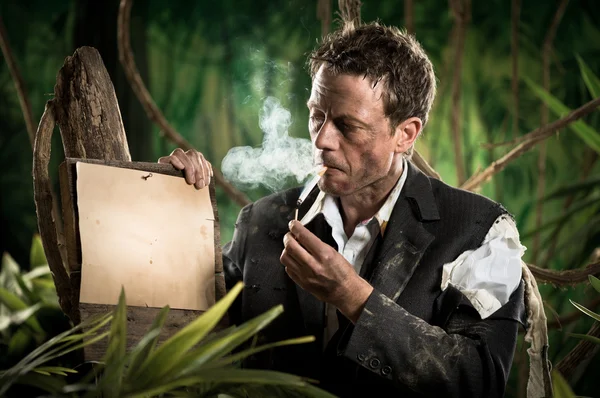 Businessman in jungle lighting cigarette — Stock Photo, Image