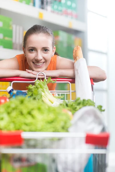 Vrouw leunend op winkelwagen — Stockfoto