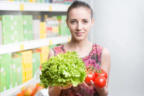 Mujer sonriendo y sosteniendo verduras — Foto de Stock