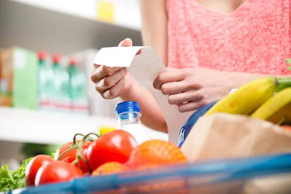 Mulher verificando recibo de supermercado longo — Fotografia de Stock