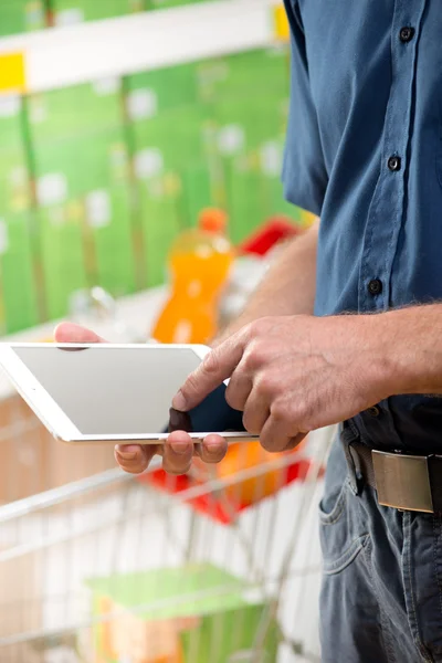 Człowiek za pomocą cyfrowego tabletu w supermarkecie — Zdjęcie stockowe