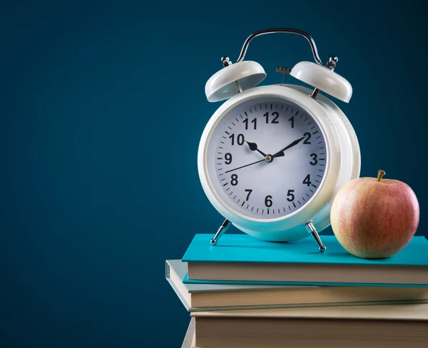 Pile of books, apple and alarm cloc — Stock Photo, Image